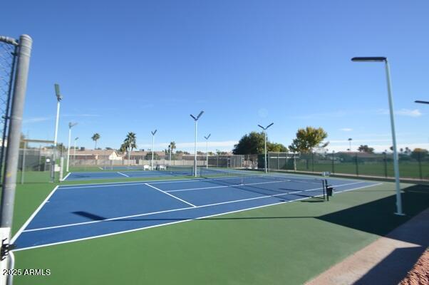 view of tennis court featuring community basketball court and fence