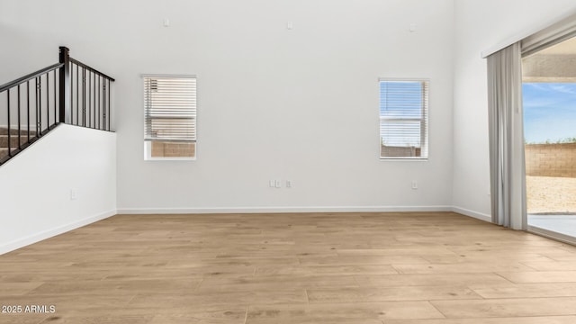 2316 W Moody Trl, Phoenix, AZ 85041 - empty room featuring light wood-style floors, baseboards, and stairs