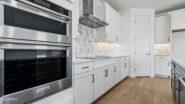 2316 W Moody Trl, Phoenix, AZ 85041 - kitchen featuring wall chimney exhaust hood, double oven, light wood finished floors, and white cabinetry