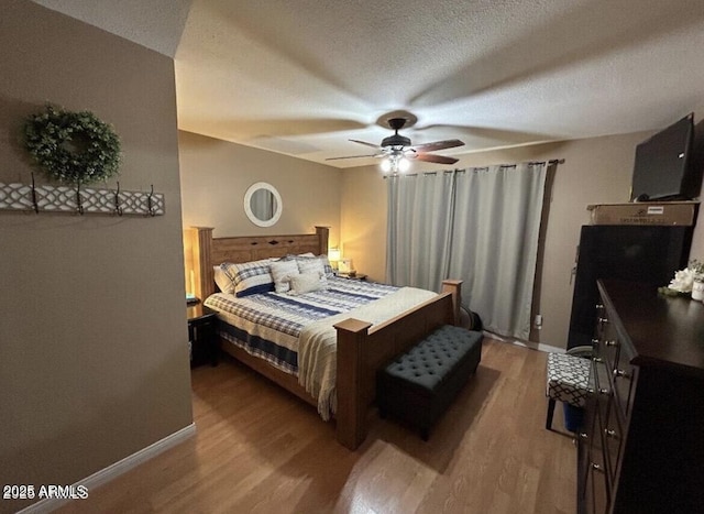 bedroom featuring a ceiling fan, light wood-style flooring, baseboards, and a textured ceiling