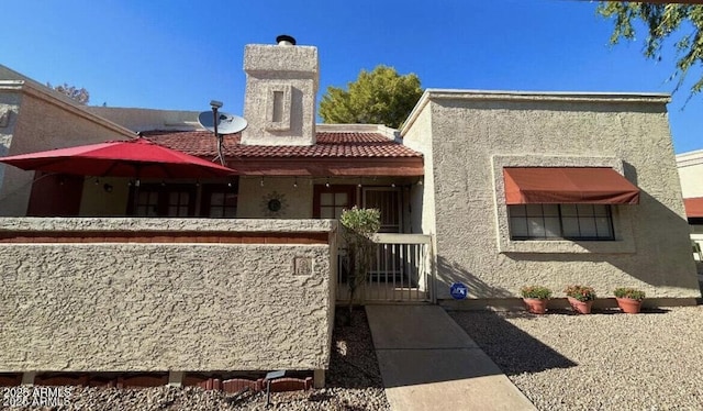 view of front of property with a tiled roof, a gate, and stucco siding