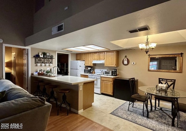 kitchen featuring light countertops, white appliances, visible vents, and under cabinet range hood