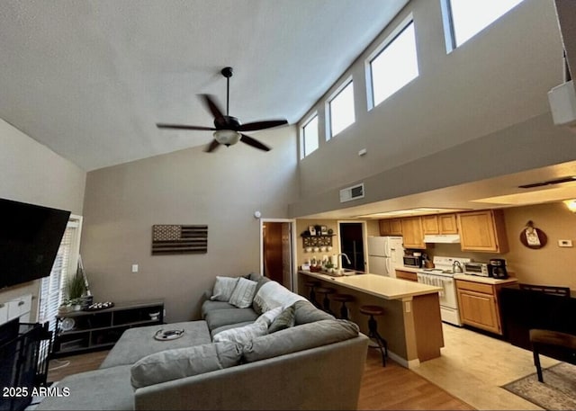 living room featuring light wood-type flooring, visible vents, and ceiling fan