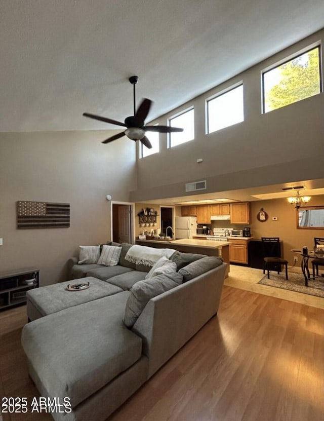 living room with a ceiling fan, visible vents, and light wood finished floors