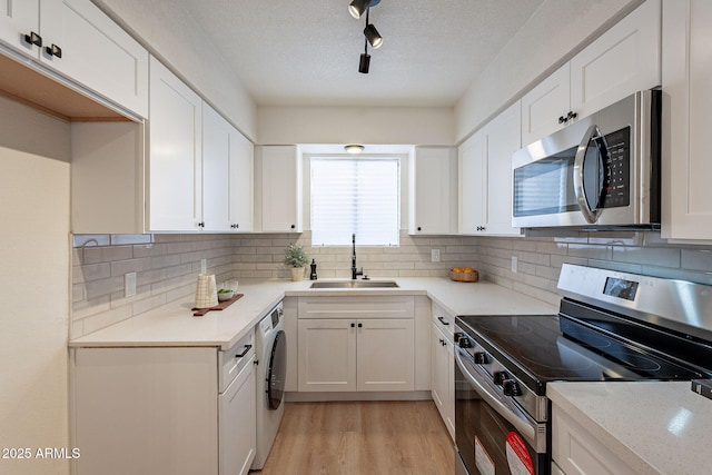 4740 E Portland St, Phoenix, AZ 85008 - kitchen featuring a sink, light wood-type flooring, appliances with stainless steel finishes, white cabinets, and washer / clothes dryer