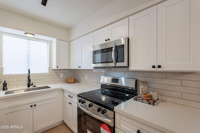 4740 E Portland St, Phoenix, AZ 85008 - kitchen featuring white cabinetry, tasteful backsplash, stainless steel appliances, and a sink