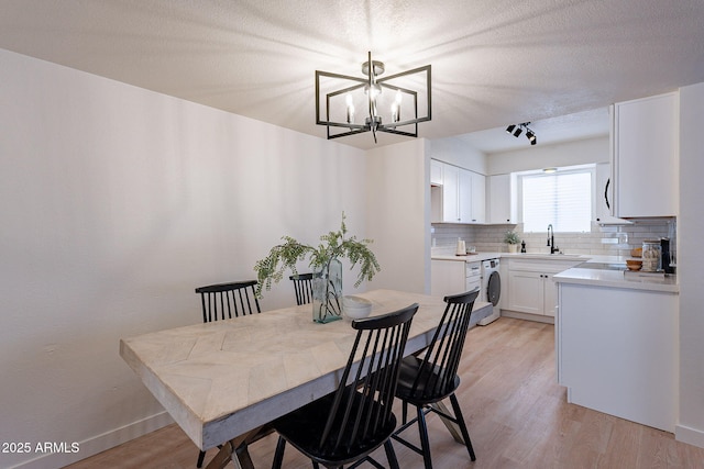 4740 E Portland St, Phoenix, AZ 85008 - dining space with an inviting chandelier, rail lighting, light wood-style floors, baseboards, and washer / clothes dryer