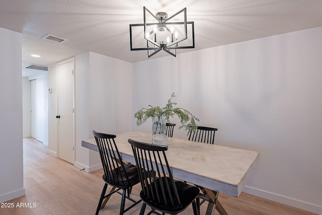 4740 E Portland St, Phoenix, AZ 85008 - dining room featuring baseboards, light wood-style flooring, visible vents, and an inviting chandelier