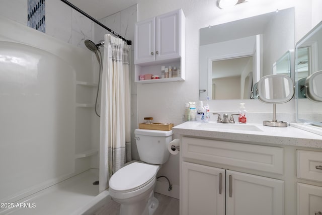 full bathroom featuring toilet, vanity, and a shower stall