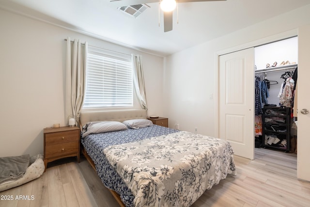 bedroom featuring light wood-style flooring, a spacious closet, visible vents, and a closet