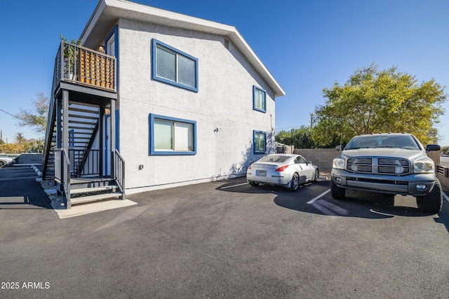 view of front of house featuring uncovered parking, stairs, and stucco siding