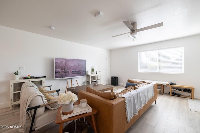 living area featuring light wood finished floors, ceiling fan, and baseboards