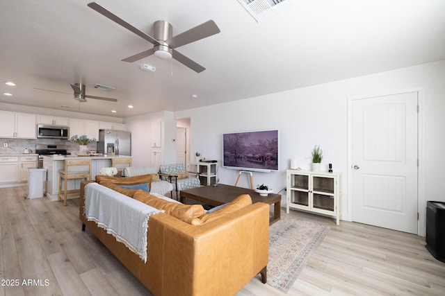 living room with light wood finished floors, visible vents, and recessed lighting