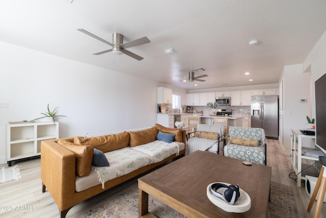 living area featuring a ceiling fan, recessed lighting, and light wood-style flooring