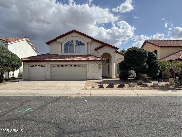 mediterranean / spanish home featuring stucco siding, a tiled roof, concrete driveway, and a garage