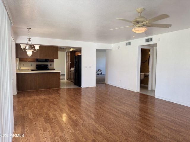 unfurnished living room with visible vents, wood finished floors, and a sink
