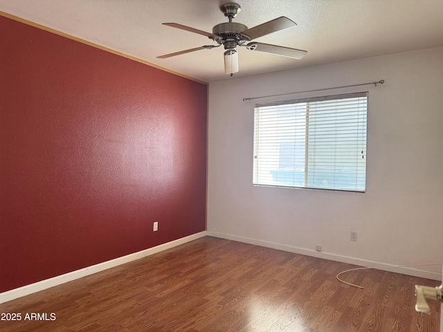 empty room with ceiling fan, wood finished floors, and baseboards