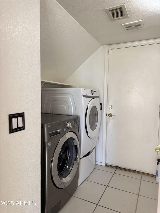 clothes washing area with light tile patterned floors, independent washer and dryer, visible vents, and laundry area