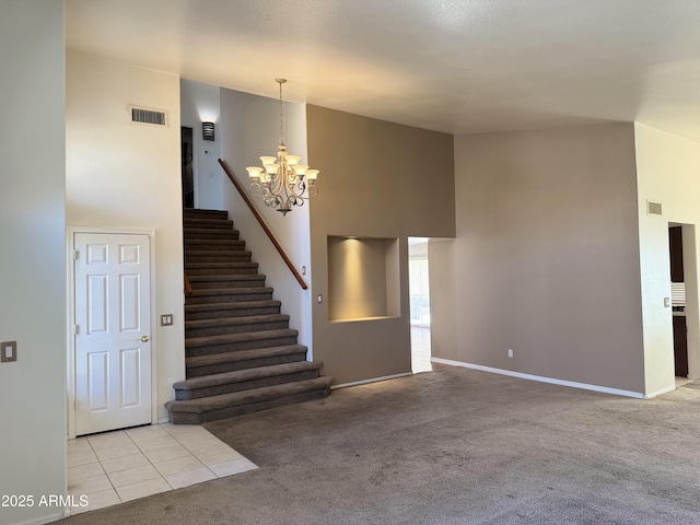 stairs featuring a high ceiling, a notable chandelier, visible vents, baseboards, and carpet floors