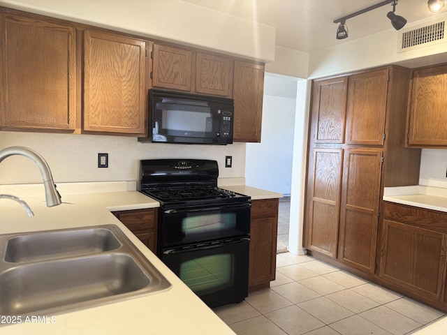 kitchen with light tile patterned floors, light countertops, black appliances, a sink, and visible vents