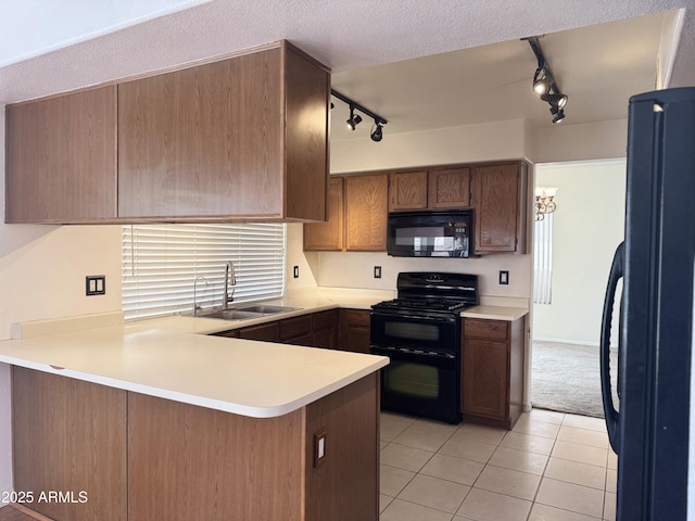 kitchen featuring light tile patterned floors, rail lighting, black appliances, a sink, and a peninsula