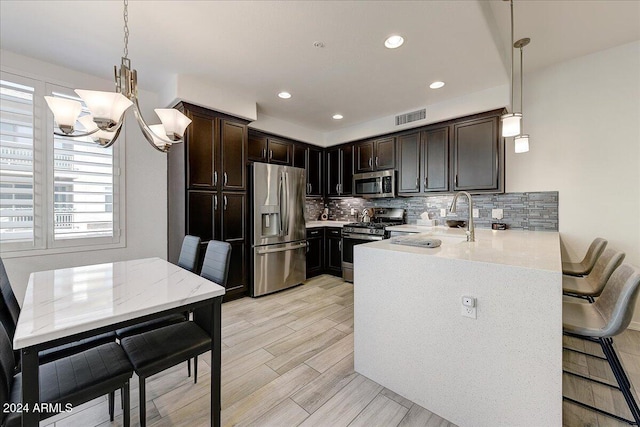 kitchen featuring tasteful backsplash, kitchen peninsula, stainless steel appliances, and decorative light fixtures