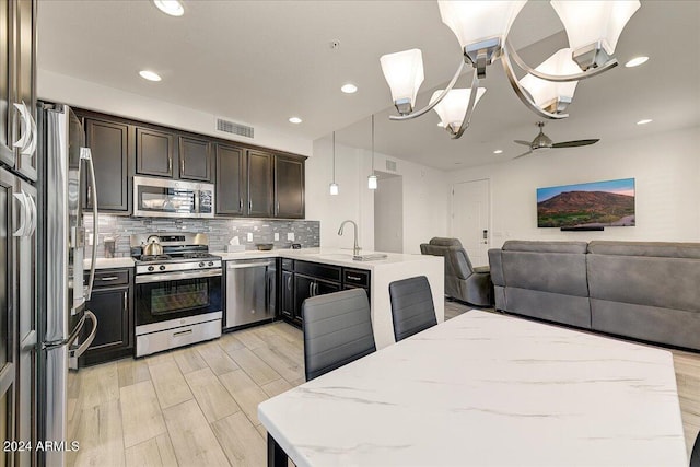 kitchen featuring light stone countertops, pendant lighting, stainless steel appliances, and sink