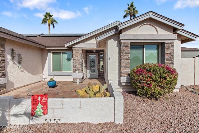 property entrance with solar panels and a patio