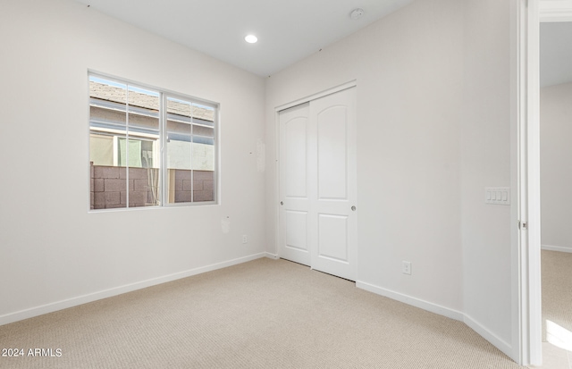 unfurnished bedroom with light carpet and a closet