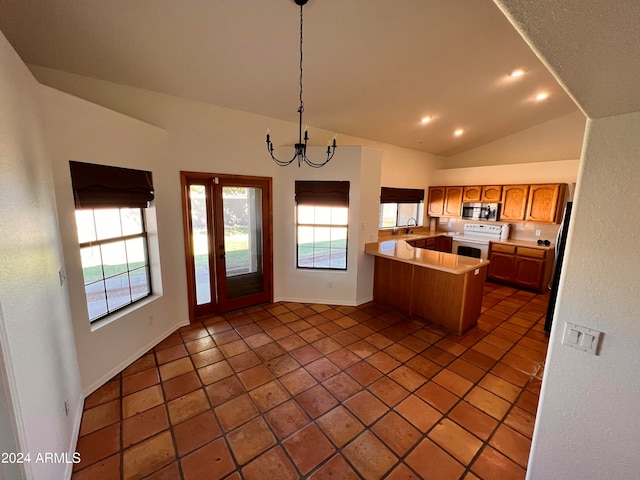 kitchen featuring dark tile patterned floors, lofted ceiling, kitchen peninsula, white range with electric cooktop, and pendant lighting