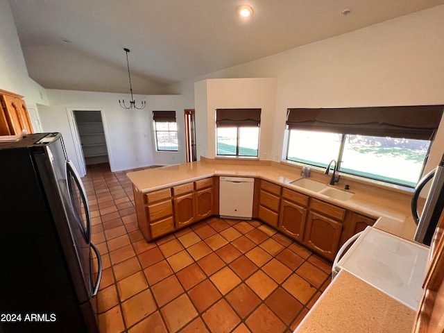 kitchen with lofted ceiling, dishwasher, sink, pendant lighting, and stainless steel refrigerator