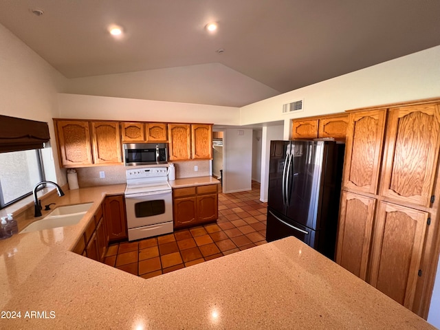 kitchen featuring sink, refrigerator, vaulted ceiling, light stone counters, and white electric range oven