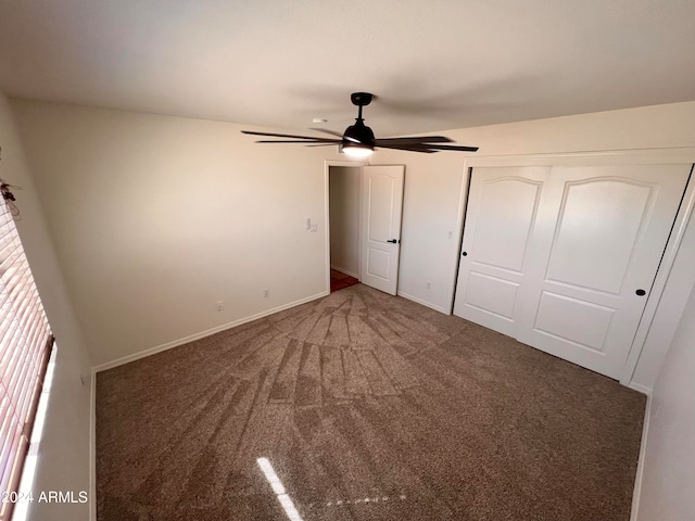 unfurnished bedroom featuring dark colored carpet, a closet, and ceiling fan