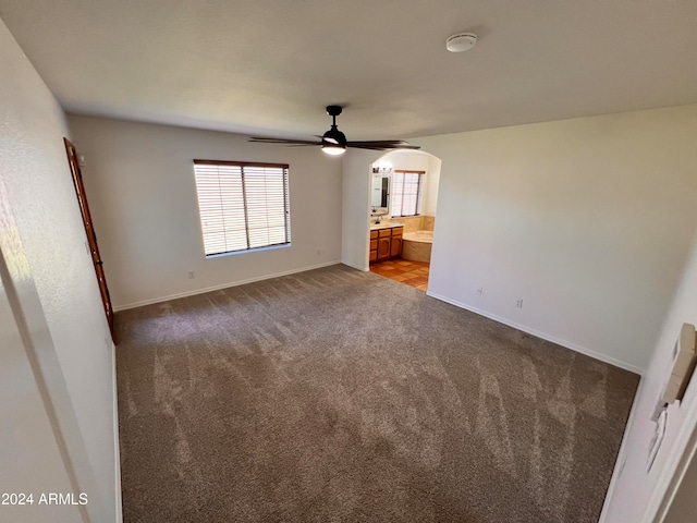 unfurnished bedroom featuring carpet, ensuite bathroom, and ceiling fan