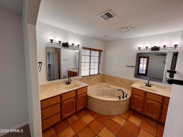 bathroom featuring vanity, a textured ceiling, a bath, and tile patterned flooring