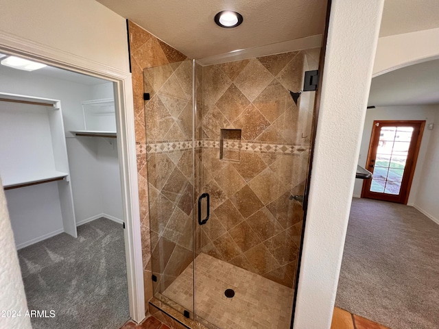 bathroom with a textured ceiling and a shower with shower door