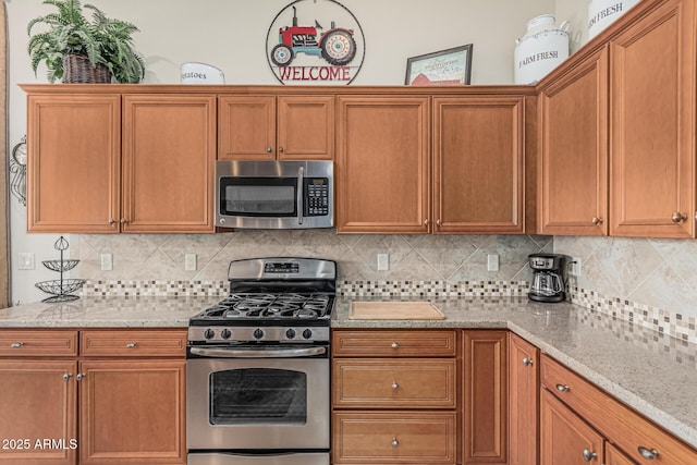 16747 W Berkeley Rd, Goodyear, AZ 85395 - kitchen with appliances with stainless steel finishes, tasteful backsplash, and light stone counters