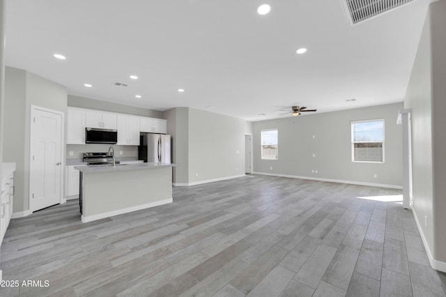 kitchen with a ceiling fan, visible vents, a center island with sink, appliances with stainless steel finishes, and white cabinetry