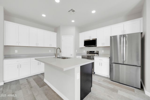 kitchen with light wood-type flooring, visible vents, a sink, white cabinetry, and stainless steel appliances