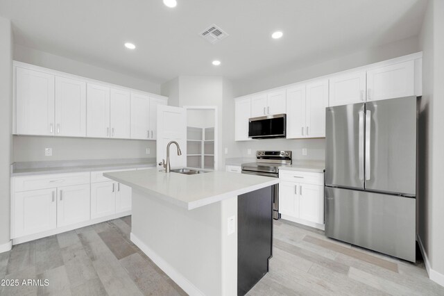 kitchen with visible vents, light wood-type flooring, appliances with stainless steel finishes, white cabinets, and a sink