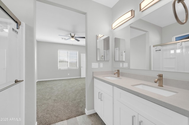 full bath featuring ceiling fan, an enclosed shower, baseboards, and a sink