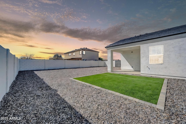 yard at dusk featuring a patio area and a fenced backyard