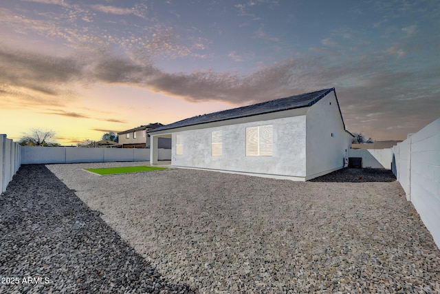 rear view of property with stucco siding, cooling unit, and a fenced backyard