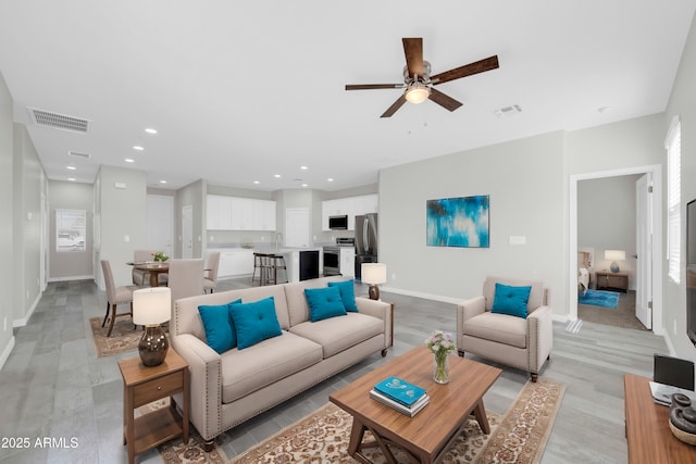 living area with recessed lighting, visible vents, baseboards, and a ceiling fan