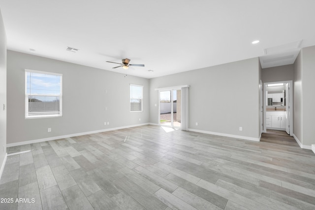 unfurnished living room with light wood-type flooring, visible vents, baseboards, and a healthy amount of sunlight