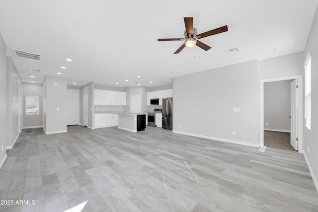 unfurnished living room with a sink, visible vents, baseboards, and recessed lighting