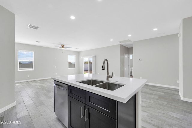 kitchen featuring stainless steel dishwasher, light countertops, open floor plan, and a sink