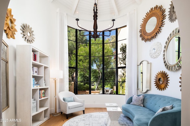 sitting room featuring beamed ceiling, hardwood / wood-style floors, and a chandelier