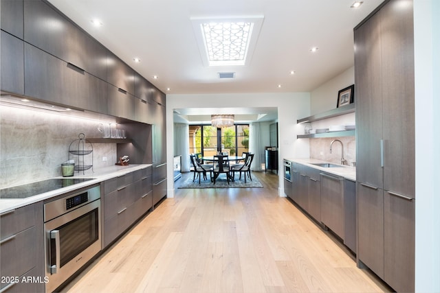 kitchen featuring tasteful backsplash, sink, oven, and light hardwood / wood-style flooring