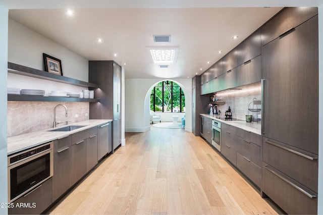 kitchen with oven, sink, dishwasher, and light wood-type flooring